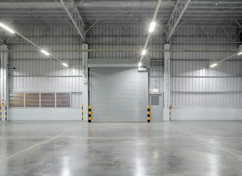Factory warehouse with roller doors and concrete flooring.